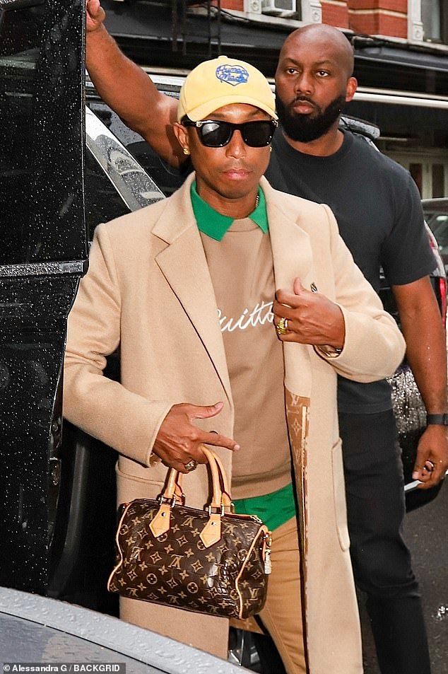 Ele completou seu conjunto com calças de bronzeado bronzeado, um boné de beisebol gráfico amarelo, óculos de sol pretos, uma bolsa marrom Louis Vuitton e sapatos de couro preto