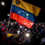 Apoiadores do presidente da Venezuela, Nicolás Maduro, agitam uma bandeira venezuelana durante um ato em defesa da paz em Caracas