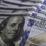 Cédulas de dólar e moedas de real, símbolo da variação cambial