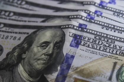 Cédulas de dólar e moedas de real, símbolo da variação cambial